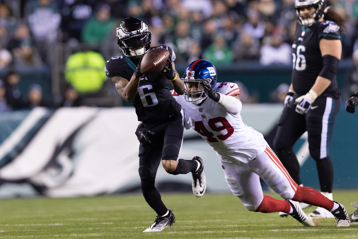 Devonta Smith puts his hands out and catches the ball as a Giants defender dives behind him in an attempt to tackle him